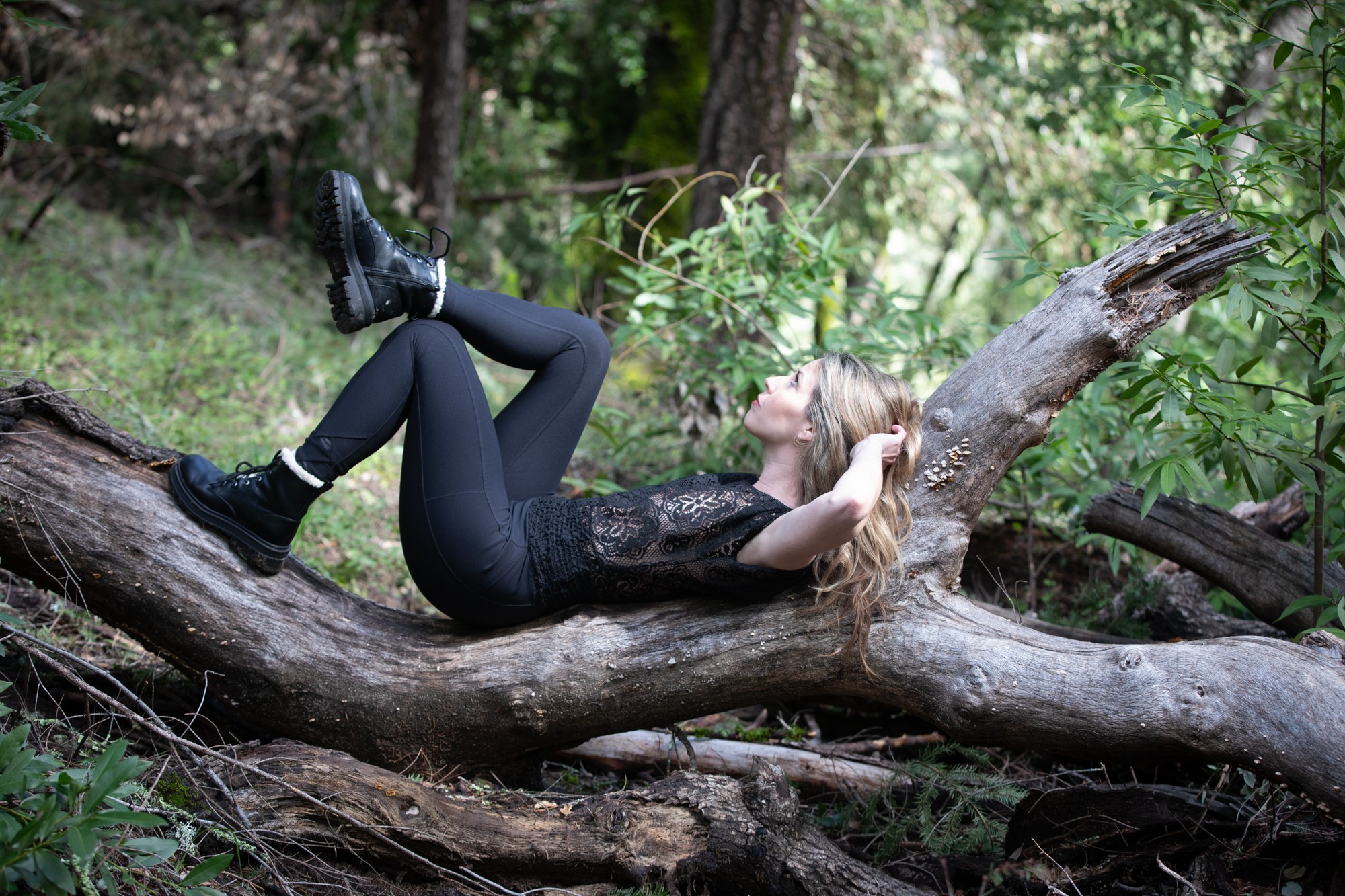 Woman relaxing on fallen log in green forest setting