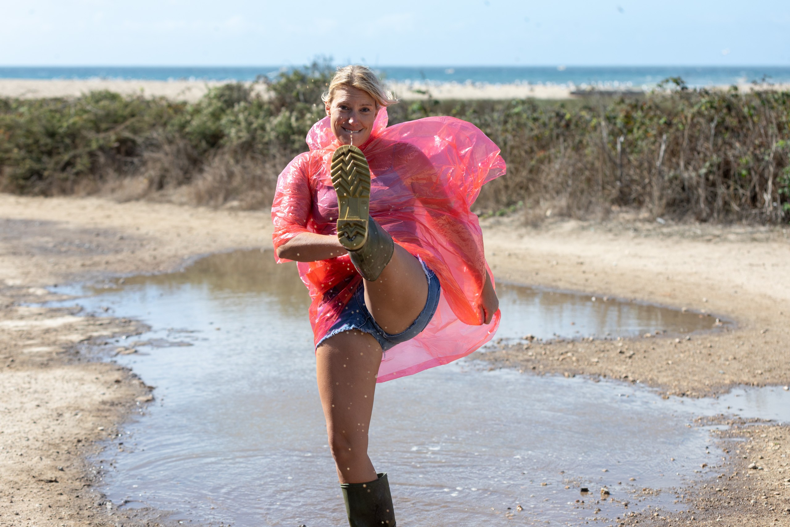 Woman jogging on beach in pink jacket, showing shoe sole