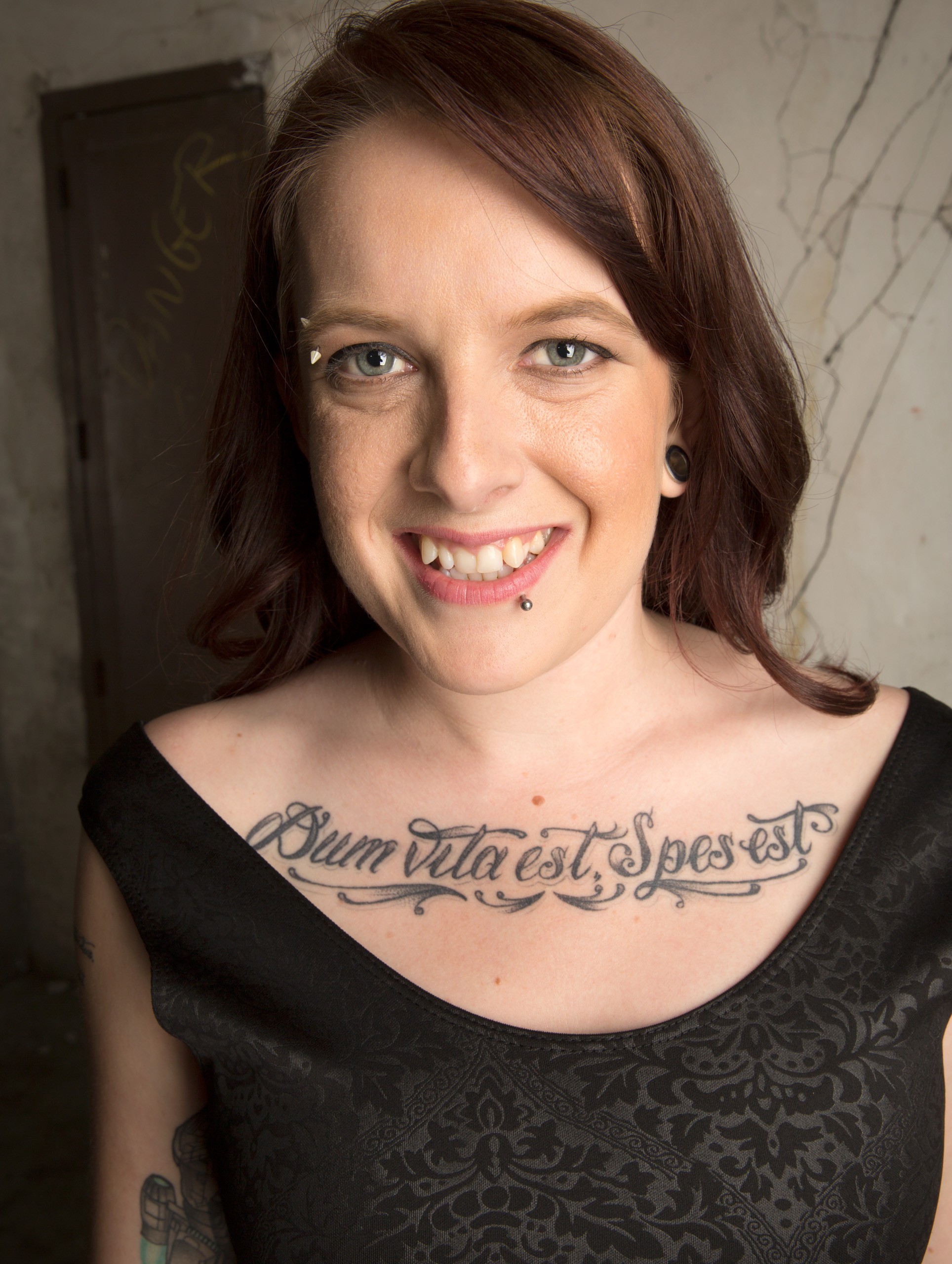 Smiling woman with chest tattoo in studio portrait