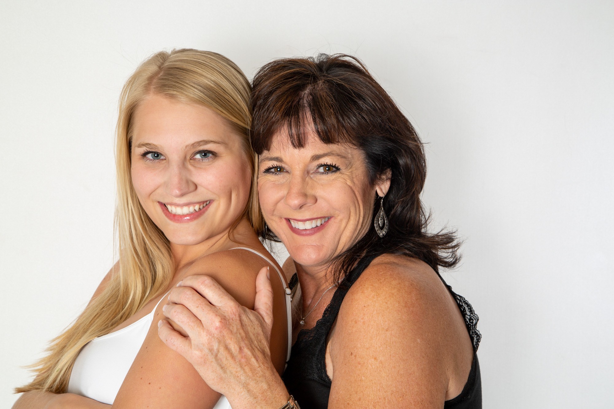 Two smiling women posing together against white background