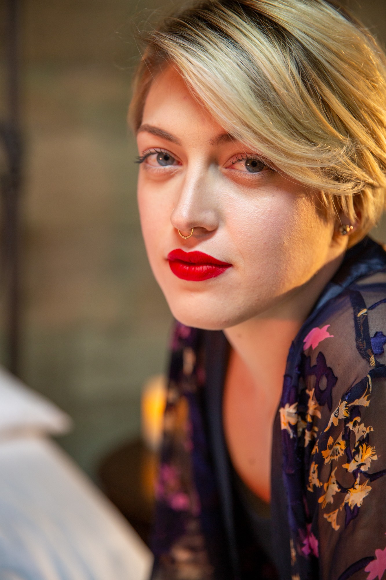 Professional headshot of woman with bold red lipstick, warm studio lighting