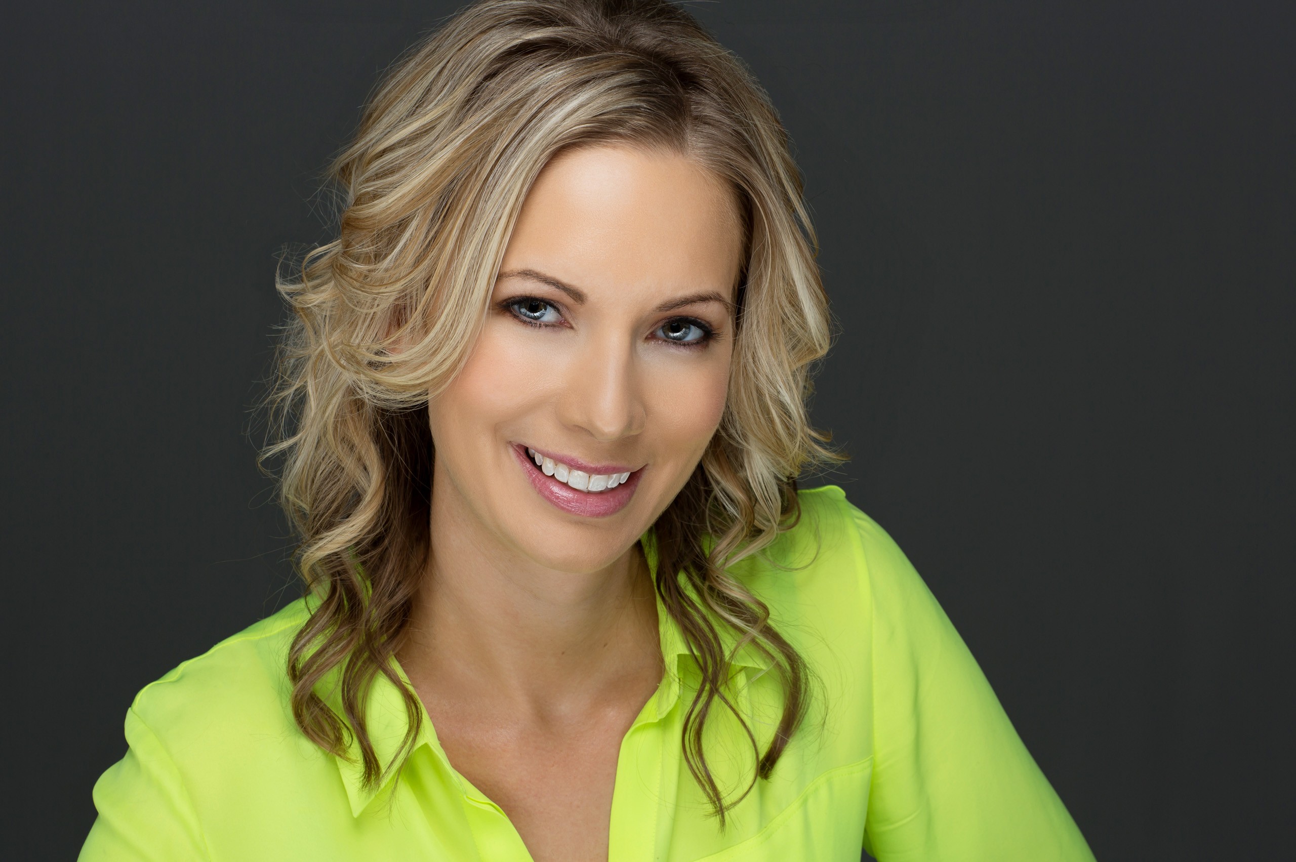 Professional headshot of smiling woman in bright yellow-green shirt